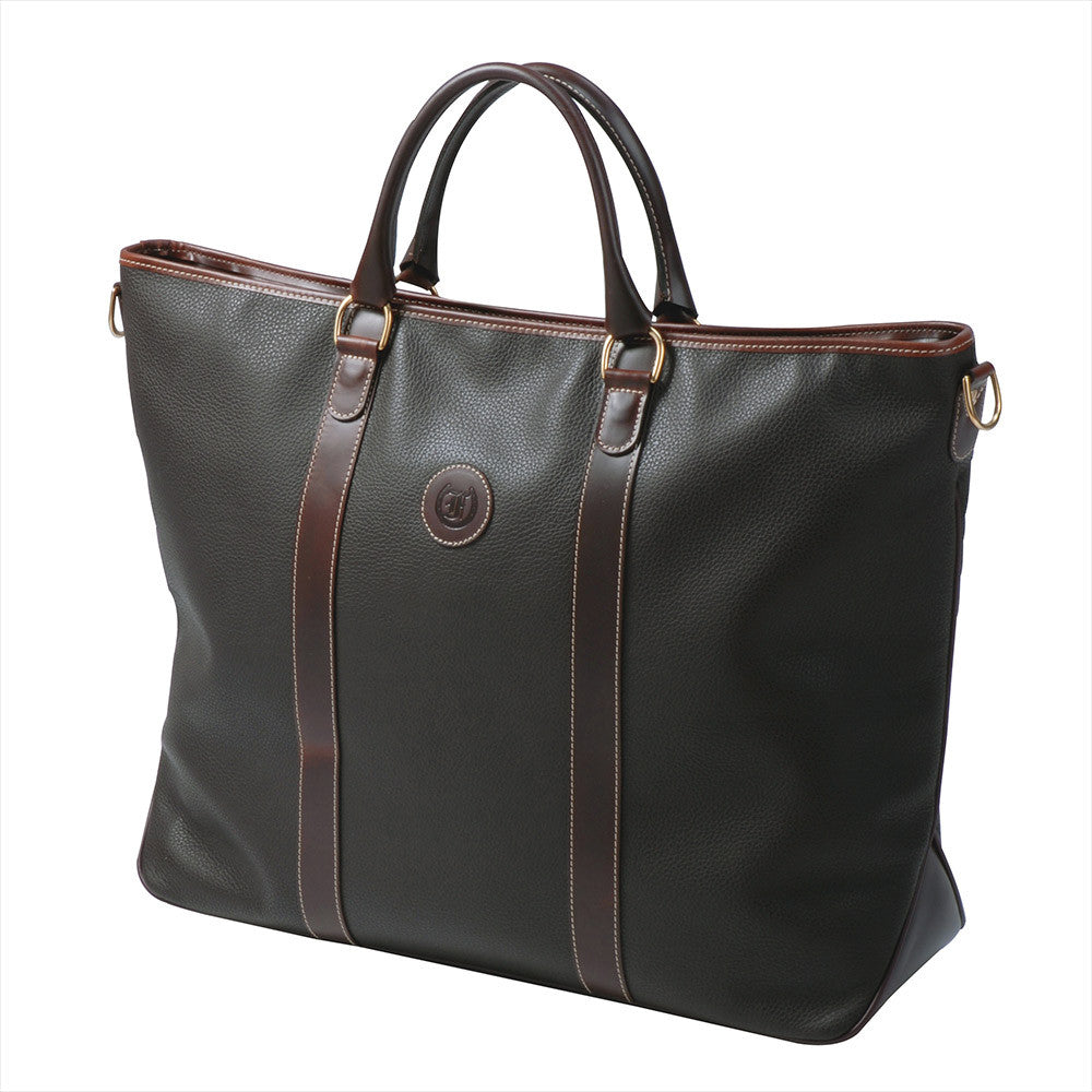 Freedman's Victoria Tote Large, dark textured leather, brown leather trim along edges and center straps, embossed circular logo on front, light contrast stitching, dual rolled handles with metal hardware, light background.