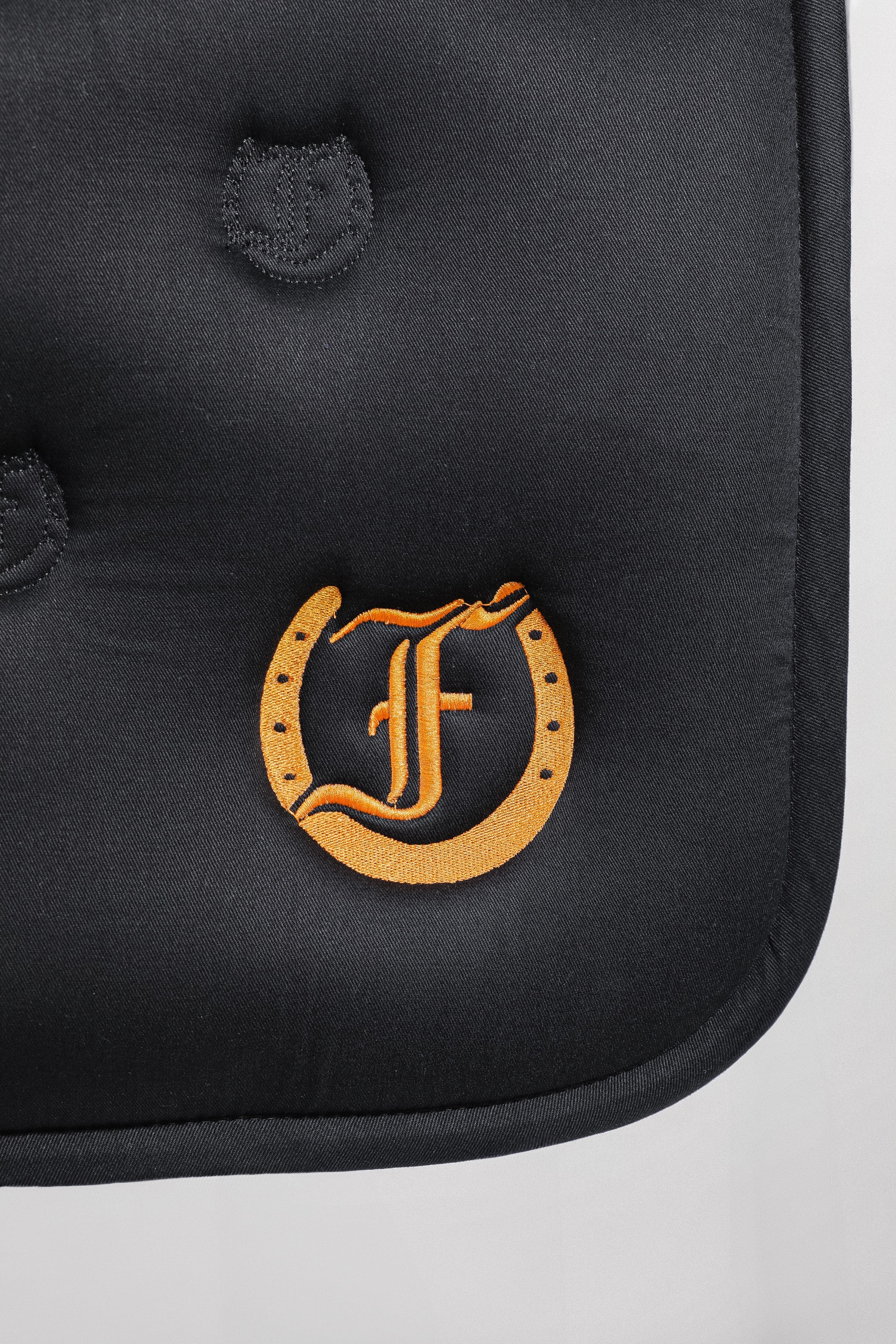 Detailed view of the Freedman's logo embroidered on a black quilted saddle pad with a bamboo lining