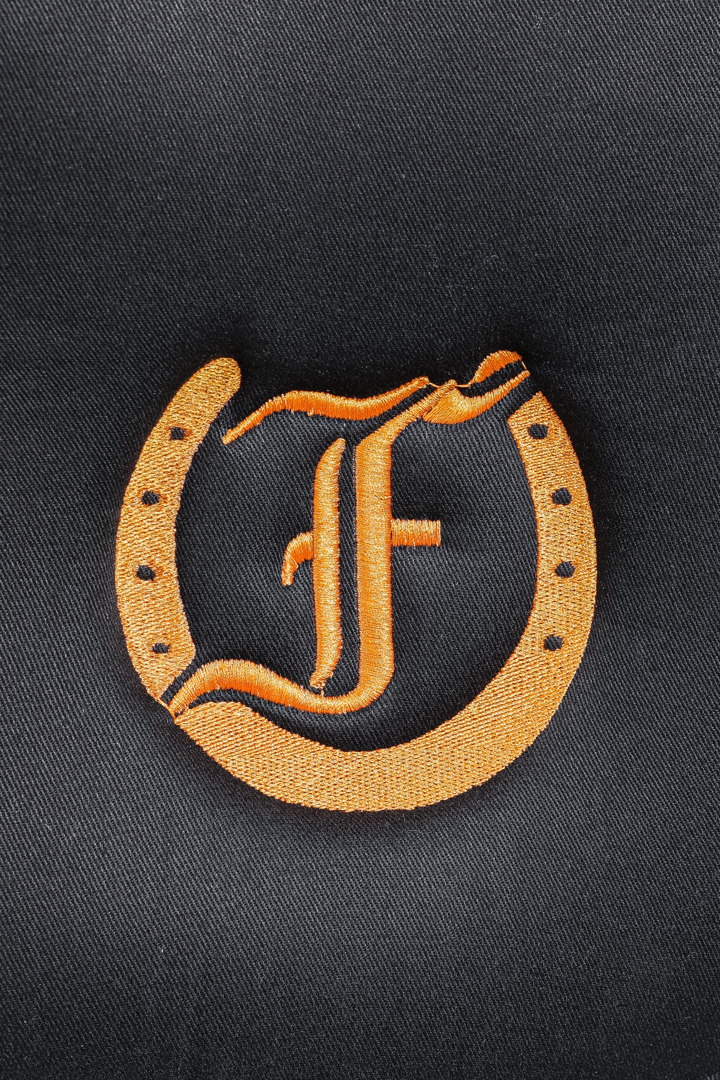 Close-up of the embroidered Freedmans's logo on a black Bamboo Lined Logo Quilted Saddle Pad.