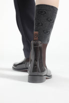 Single black patent leather Adelaide Show Jodhpur Boot on a person's foot, with patterned socks visible, from a rear perspective.