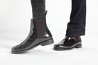  Pair of black patent leather Adelaide Show Jodhpur Boots on a person's feet, with patterned socks visible