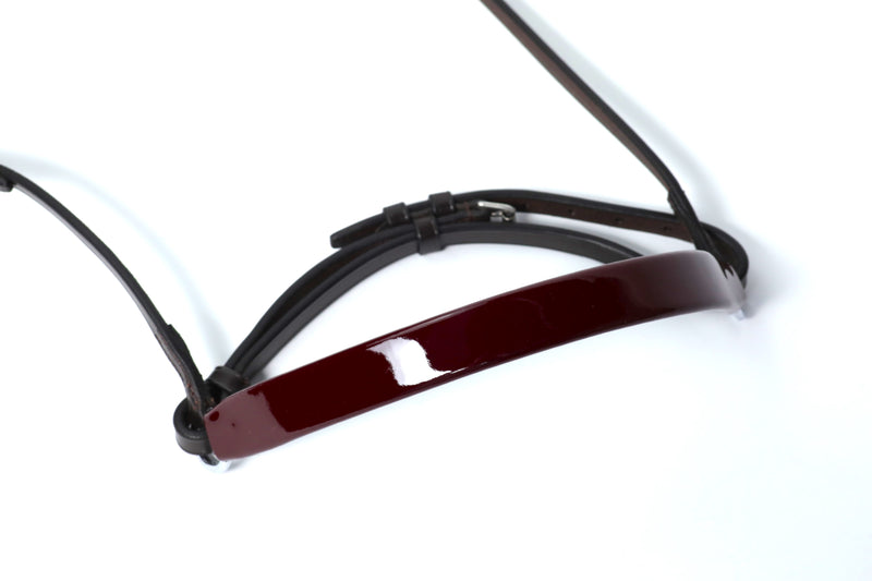 Close-up of Burgundy patent leather Show Cavesons with black leather straps, displayed on a white background.