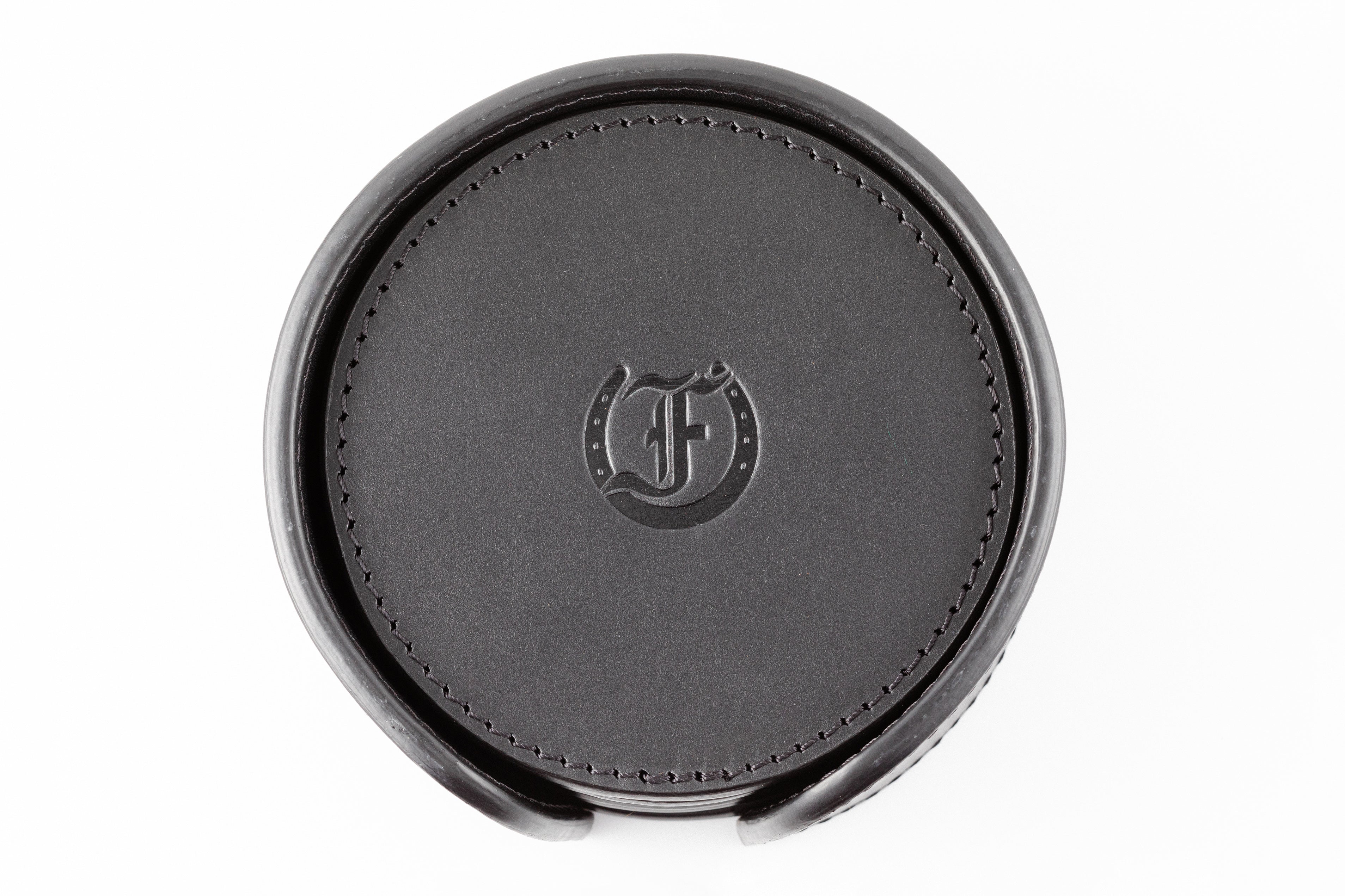 Freedman's Coaster Set in Holder: Black Leather Coasters with Embossed Freedman’s Logo in Center, Close-Up View