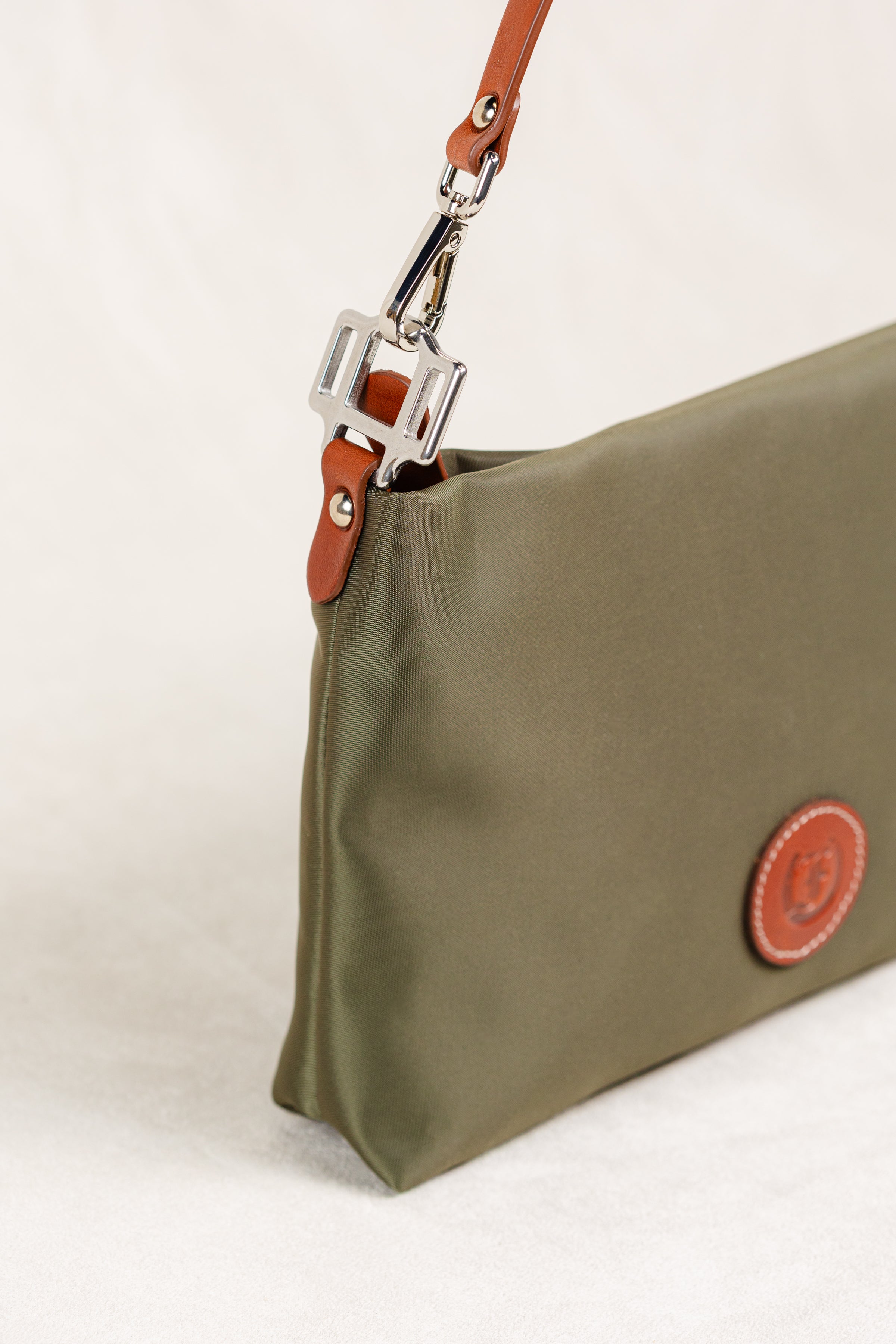 Dokar Bag by Freedman's, close-up shot of the olive green bag showing the silver hardware attachment of the brown leather strap, fabric texture, and side profile of the bag.