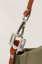 Dokar Bag by Freedman's, macro shot of the silver metal clasp and brown leather strap attachment on the olive green bag, showing fine detail.
