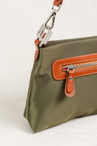 Freedman's Dokar Bag in olive green, detail shot showing the silver hardware clasp, brown leather strap, and the front zipper pocket with brown leather and red zipper teeth.