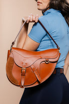 A woman in a blue top and dark pants holds the Freedman's Burghley Shoulder Bag on the shoulder.