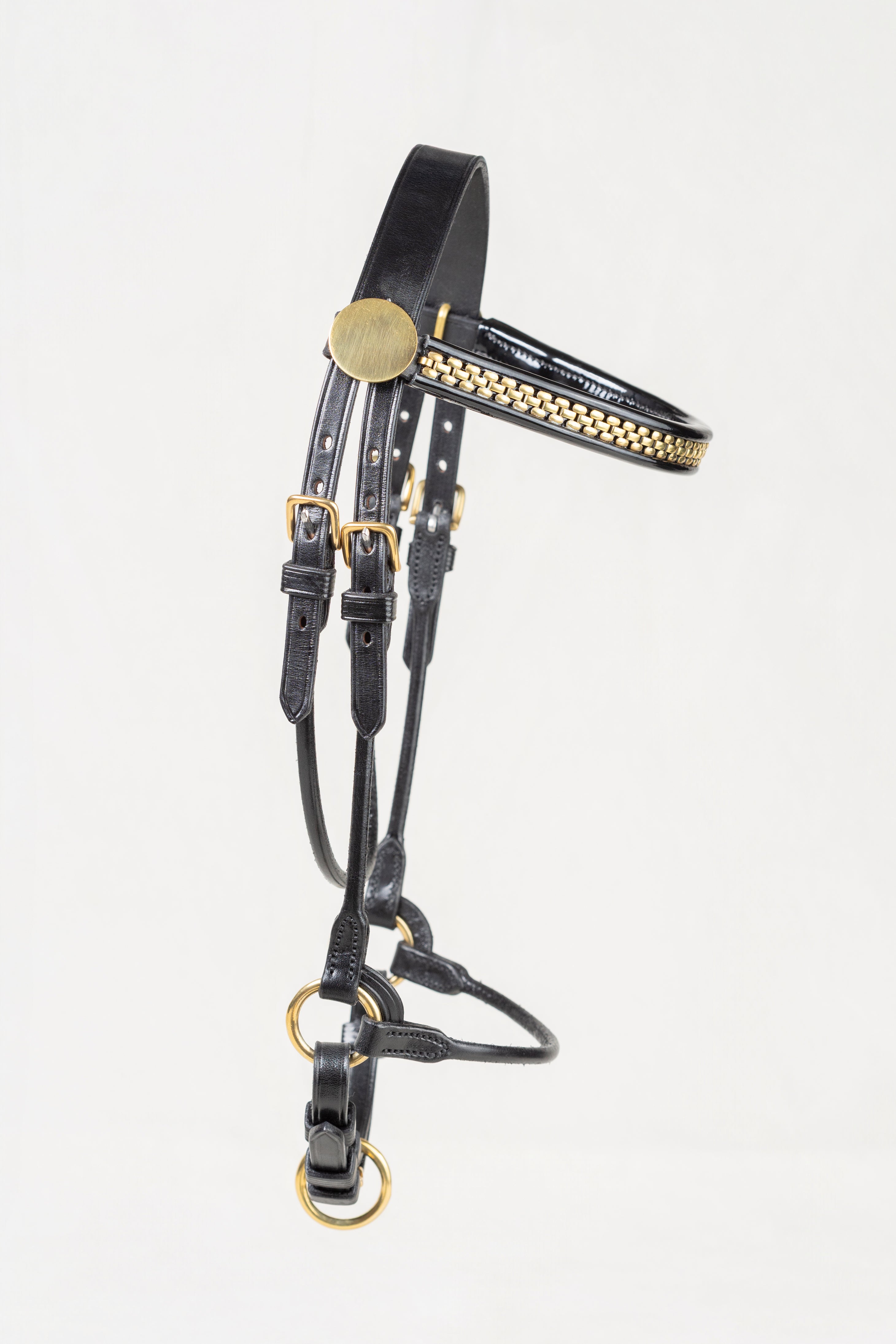 Black leather horse bridle with gold-tone metal accents and a decorative gold patterned bit, shown against a plain white background.