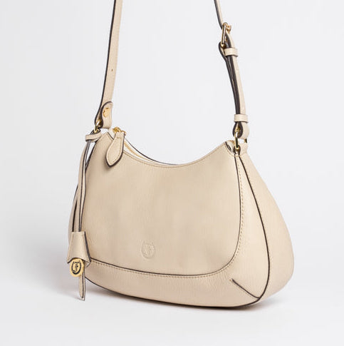 Side view of Carlisle Bag in putty leather by Freedman Harness – structured crossbody bag with gold logo charm, curved silhouette, and adjustable strap