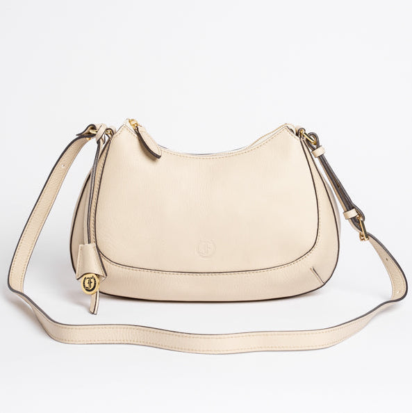 Carlisle Bag in putty leather by Freedman Harness – curved beige crossbody handbag with gold hardware, adjustable strap, and minimalist silhouette