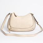Carlisle Bag in putty leather by Freedman Harness – curved beige crossbody handbag with gold hardware, adjustable strap, and minimalist silhouette
