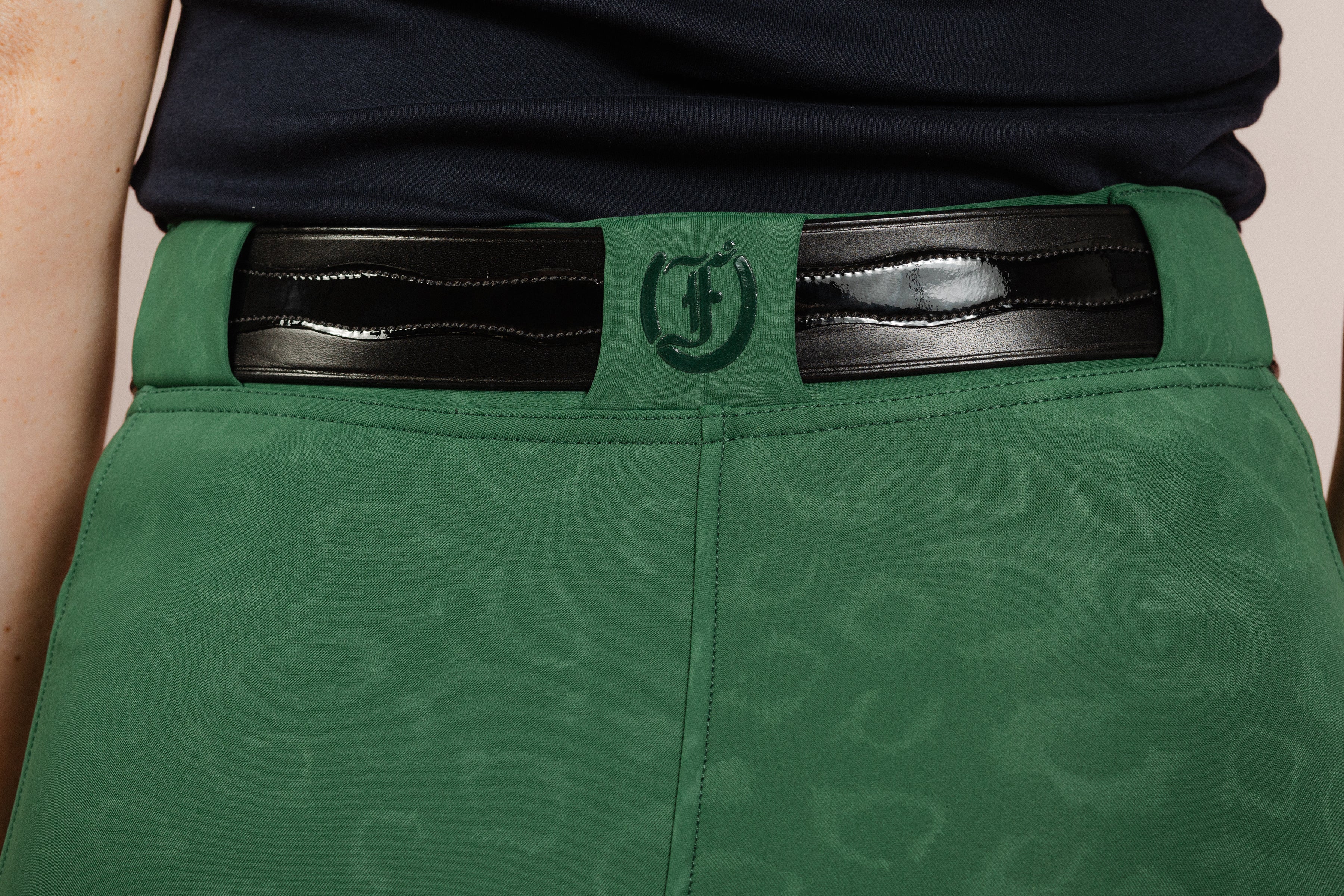 Back view of Green Cheetah Jods with a Patent Scalloped Spur Belt and Freedman’s “F” logo by Freedman’s Harness on a beige background.