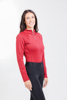 Woman wearing the Tess Ladies' 1/4 Zip Long Sleeve Top by Freedman's in a stylish red color, designed for comfort and performance in equestrian and activewear fashion.
