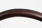 Close-up of curved, dark brown leather, highlighting the detailed stitching along the edge, against a white background.