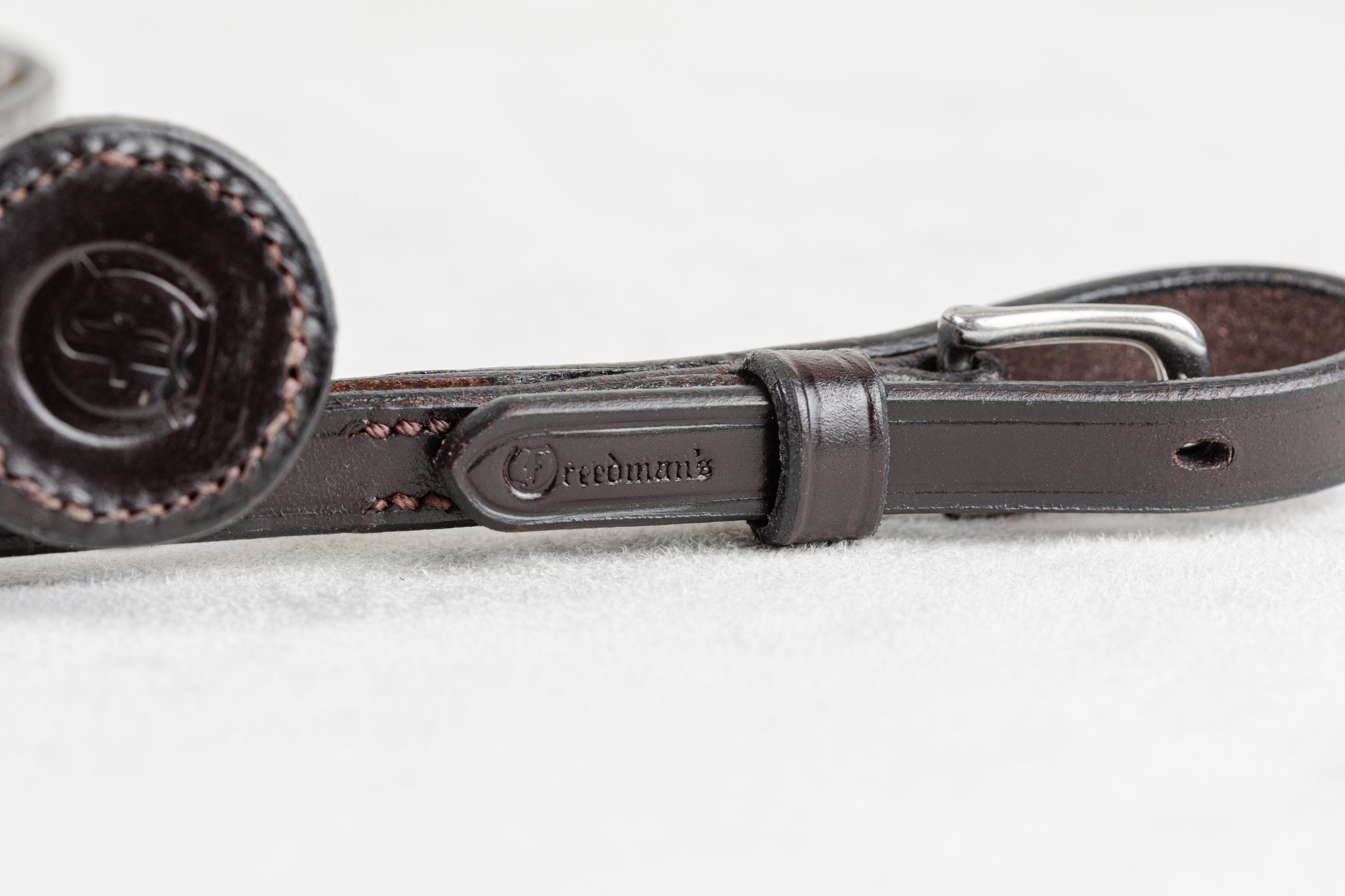 Brown leather belt with a visible brand logo on a light gray background