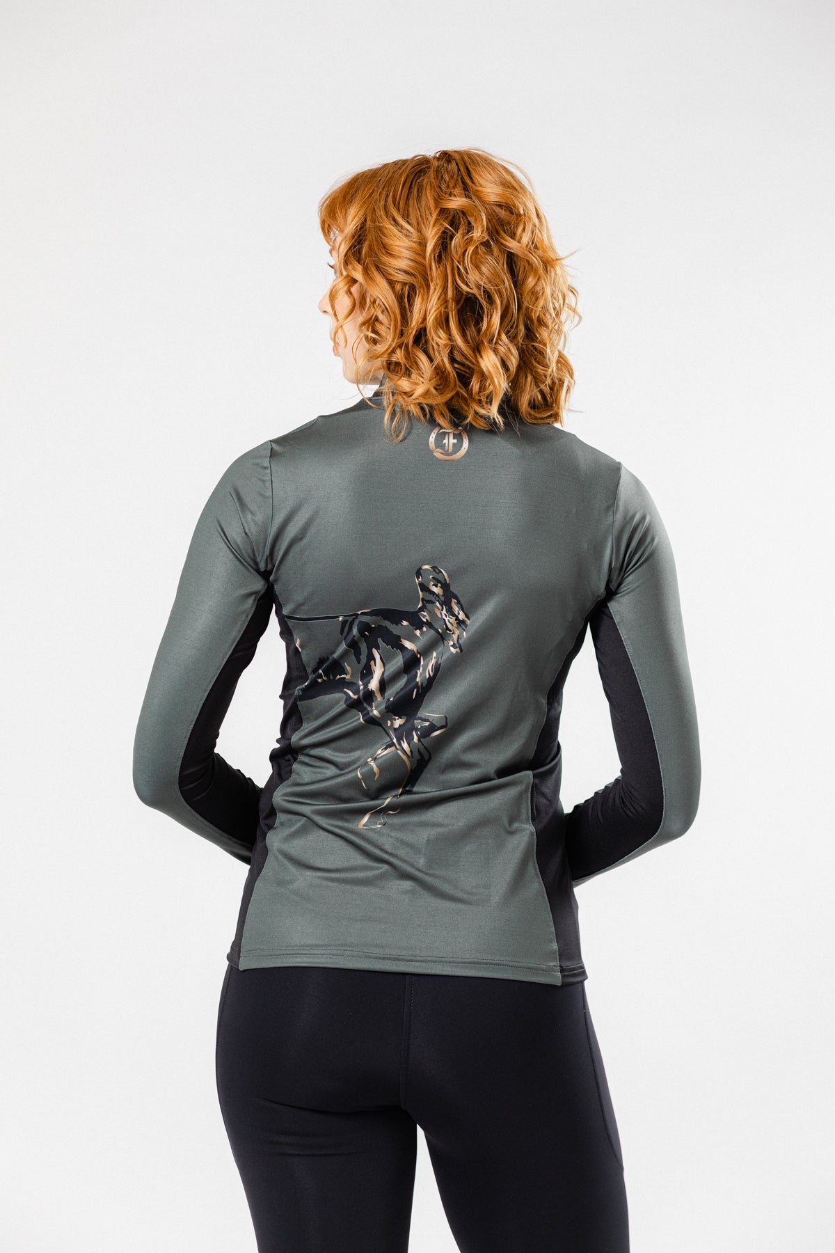 Model wearing the Midas 1/4 Zip Long Sleeve Shirt by Freedman's, featuring a stylish horse print design on a sleek, dark green athletic top with gold accents. Back view