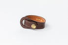 
Brown leather Signature Leather Bracelet by Freedman's with brass logo button and white stitching, displayed on a white background.