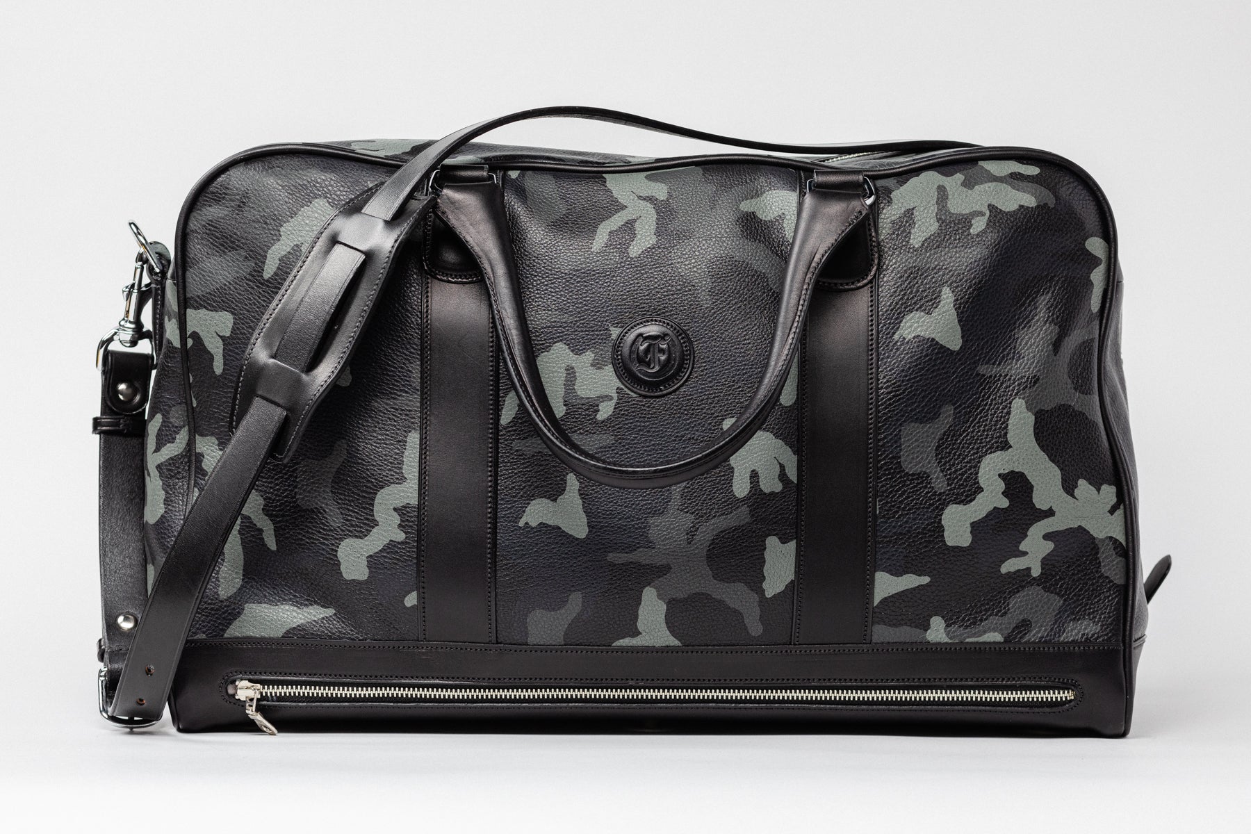 Freedman's Grand Break Duffel, camouflage patterned leather, dark leather trim at base and sides, dual rolled handles, detachable shoulder strap with padded section, embossed logo, silver zipper closure, light background