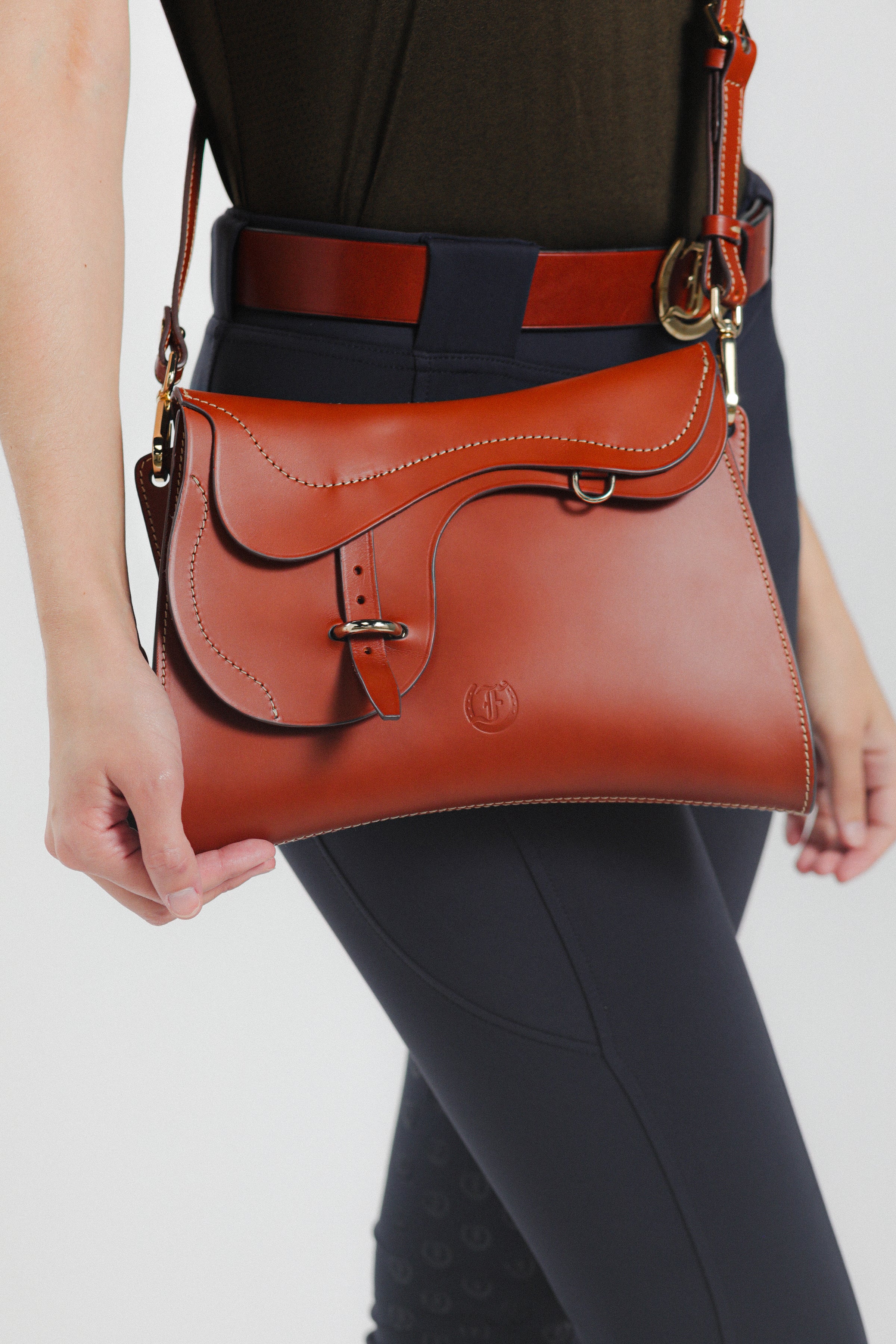 Model wearing Trooper Shoulder Bag in cognac leather by Freedman Harness – equestrian-inspired crossbody with curved flap and contrast stitching