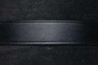 Black leather belt strap, close-up showing texture and construction.