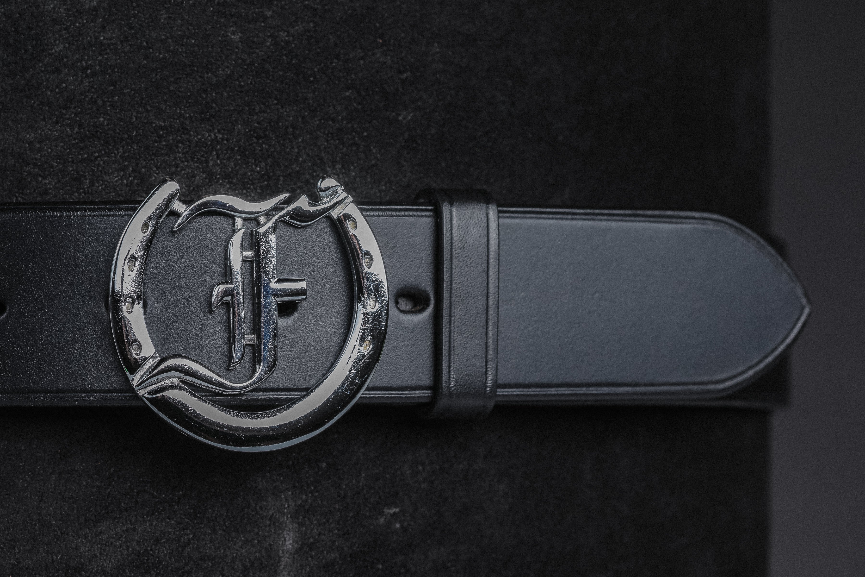 Close up of Freedman's Signature Logo Belt: Black Leather Belt with Silver Horseshoe Buckle and Embossed Brand Logo