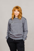Woman wearing the Ash Grey Freedman's embroidered crewneck sweatshirts. These stylish and cozy sweatshirts feature a tonal Freedman’s logo, perfect for casual wear and layering