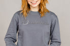 Woman wearing the Ash Grey Freedman's embroidered crewneck sweatshirts. These stylish and cozy sweatshirts feature a tonal Freedman’s logo, perfect for casual wear and layering