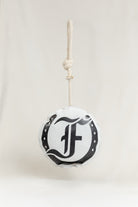 Round horse toy featuring the black Freedman logo and horseshoe graphic, hanging from a knotted rope on a light beige background