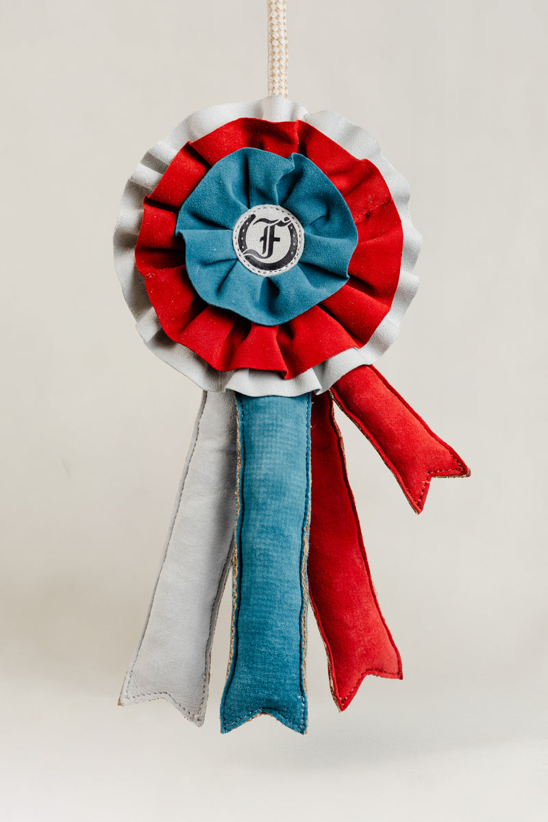 Decorative equestrian ribbon toy in red, blue, and white with the Freedman logo, hanging against a white background.