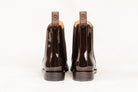 Back view of a pair of brown patent leather Adelaide Show Jodhpur Boots, isolated on a white background.