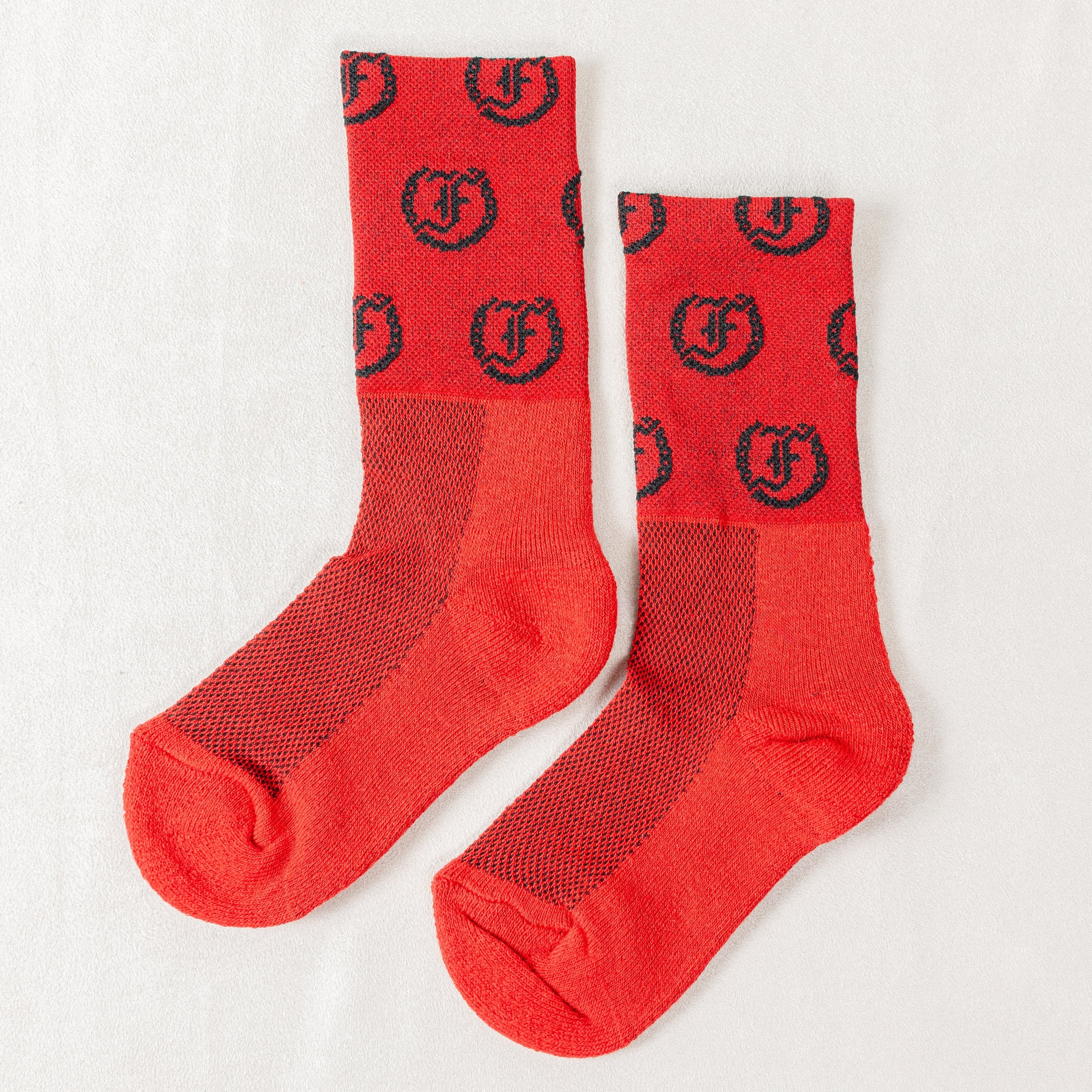 Red socks with repeating black Freedman's logo, laid flat with visible details and pattern.