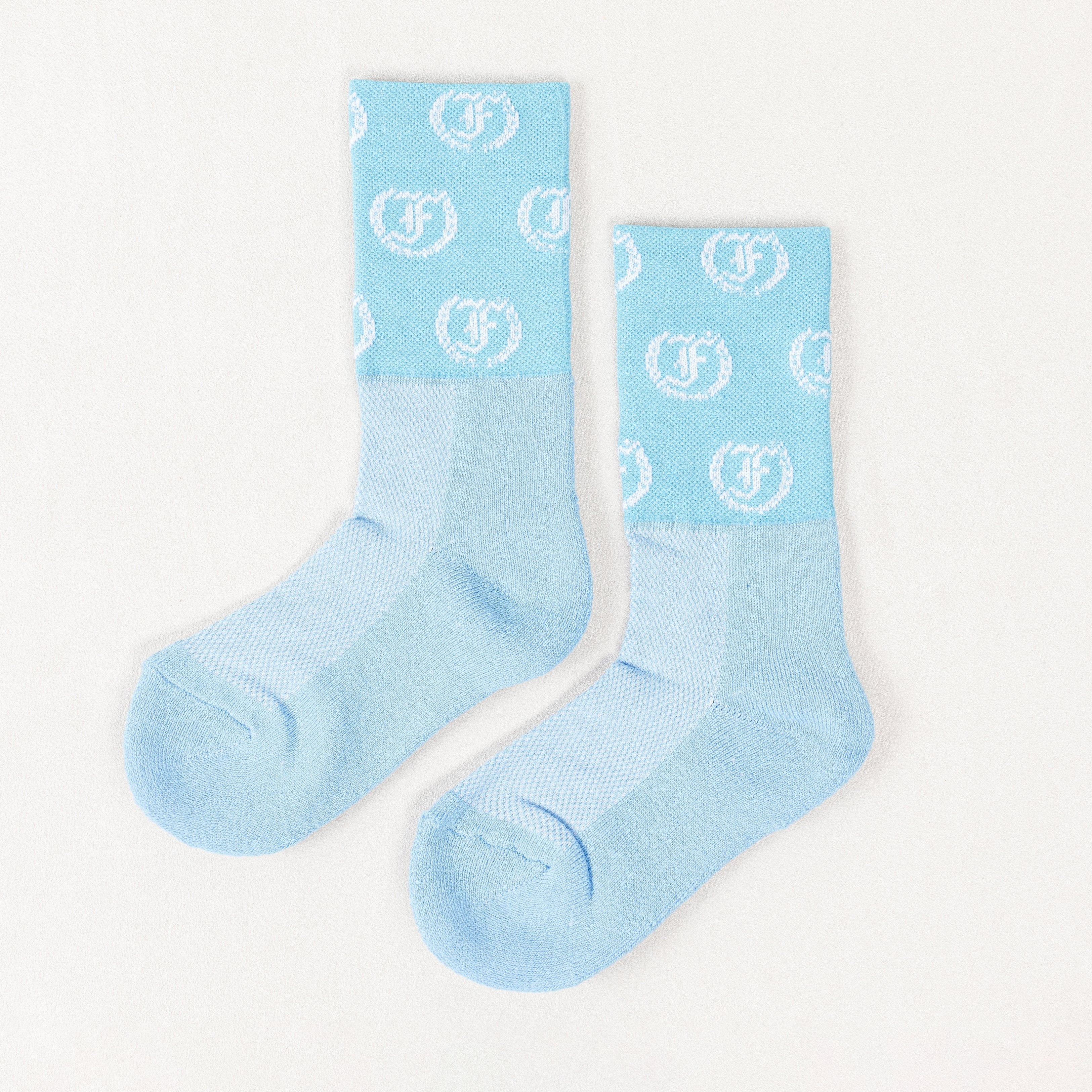 Light blue socks with repeating light circular Freedman's logo pattern, laid flat with visible heel and toe details, white background.