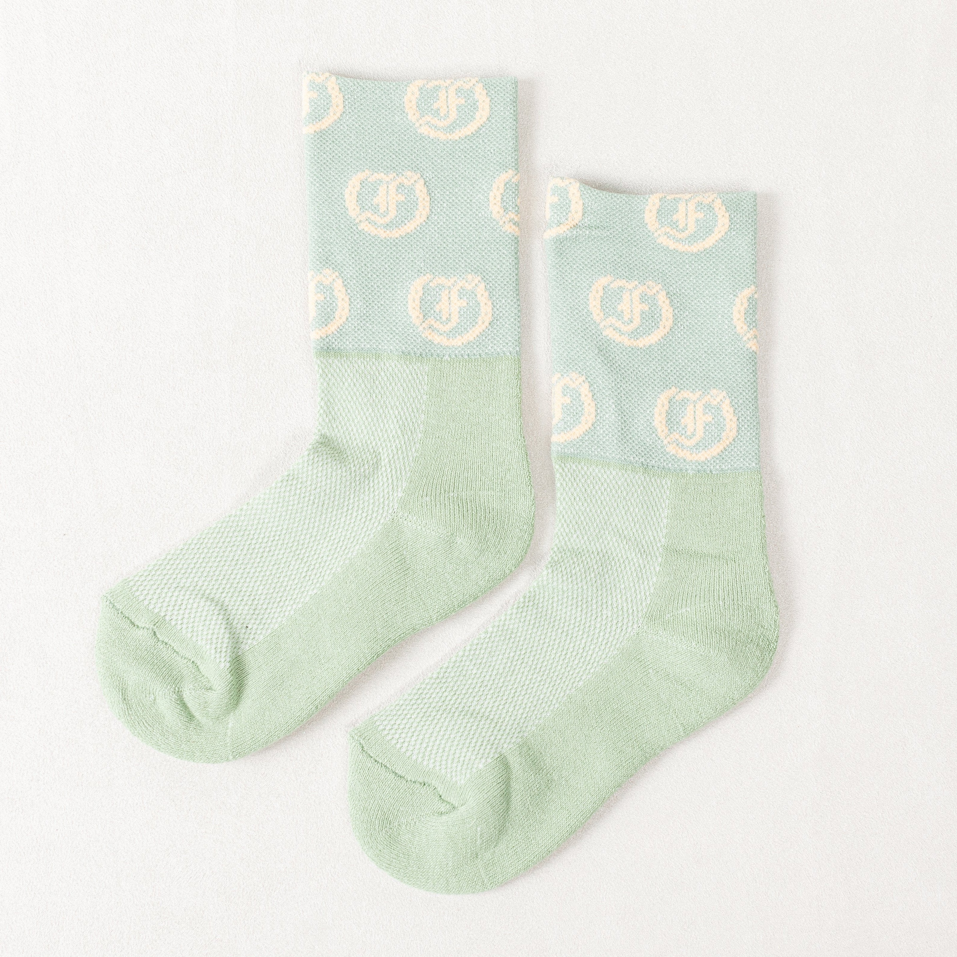 Light green socks with repeating light Freedman's logo, laid flat with visible details and pattern.