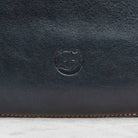 close-up of Freedman's Logo on Dark Navy Leather Murphy Bag with Orange Stitching