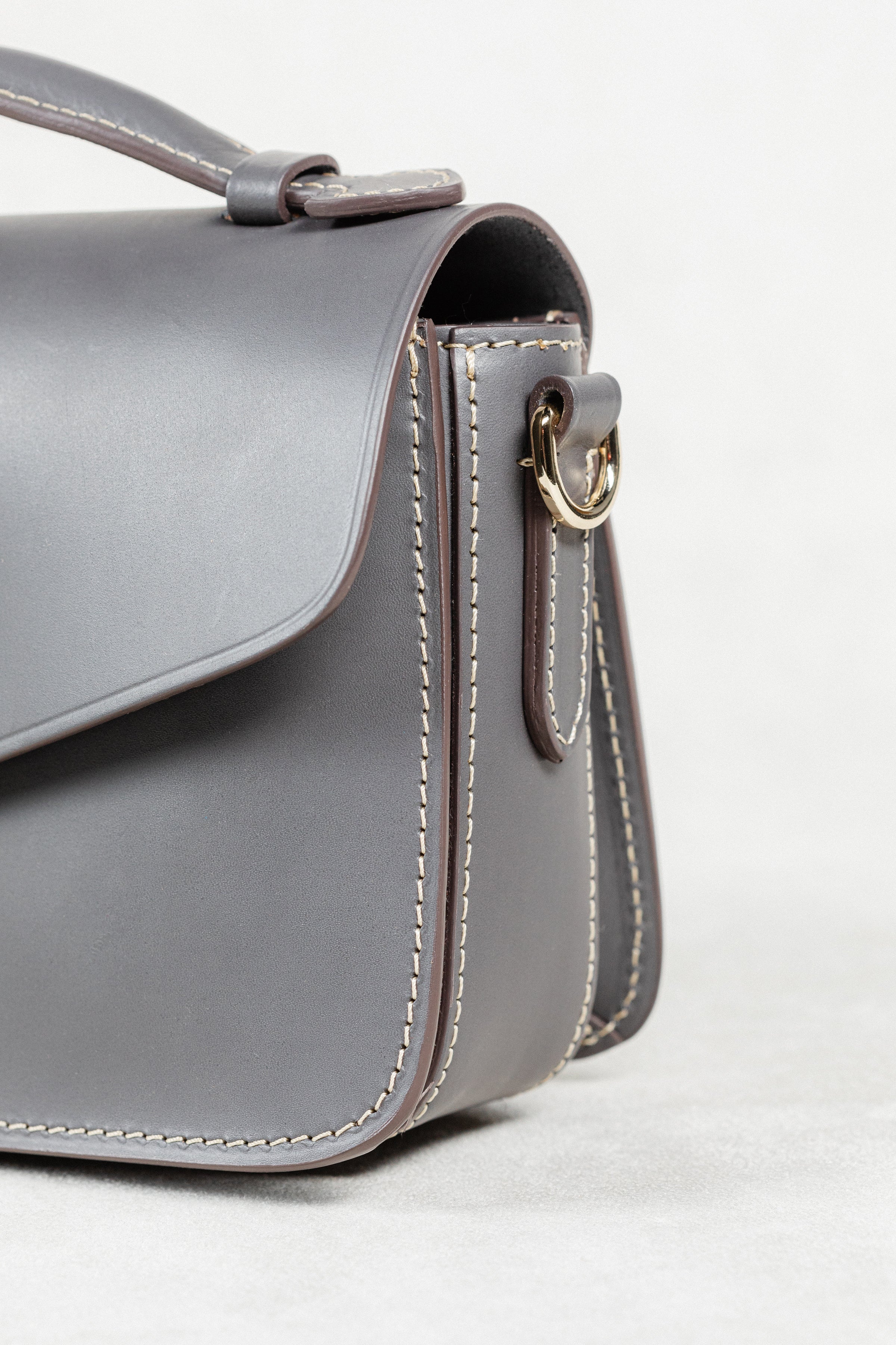 Close-up angled view of grey leather Mantelet Bag by Freedman's, showing gold-tone hardware and stitching details.