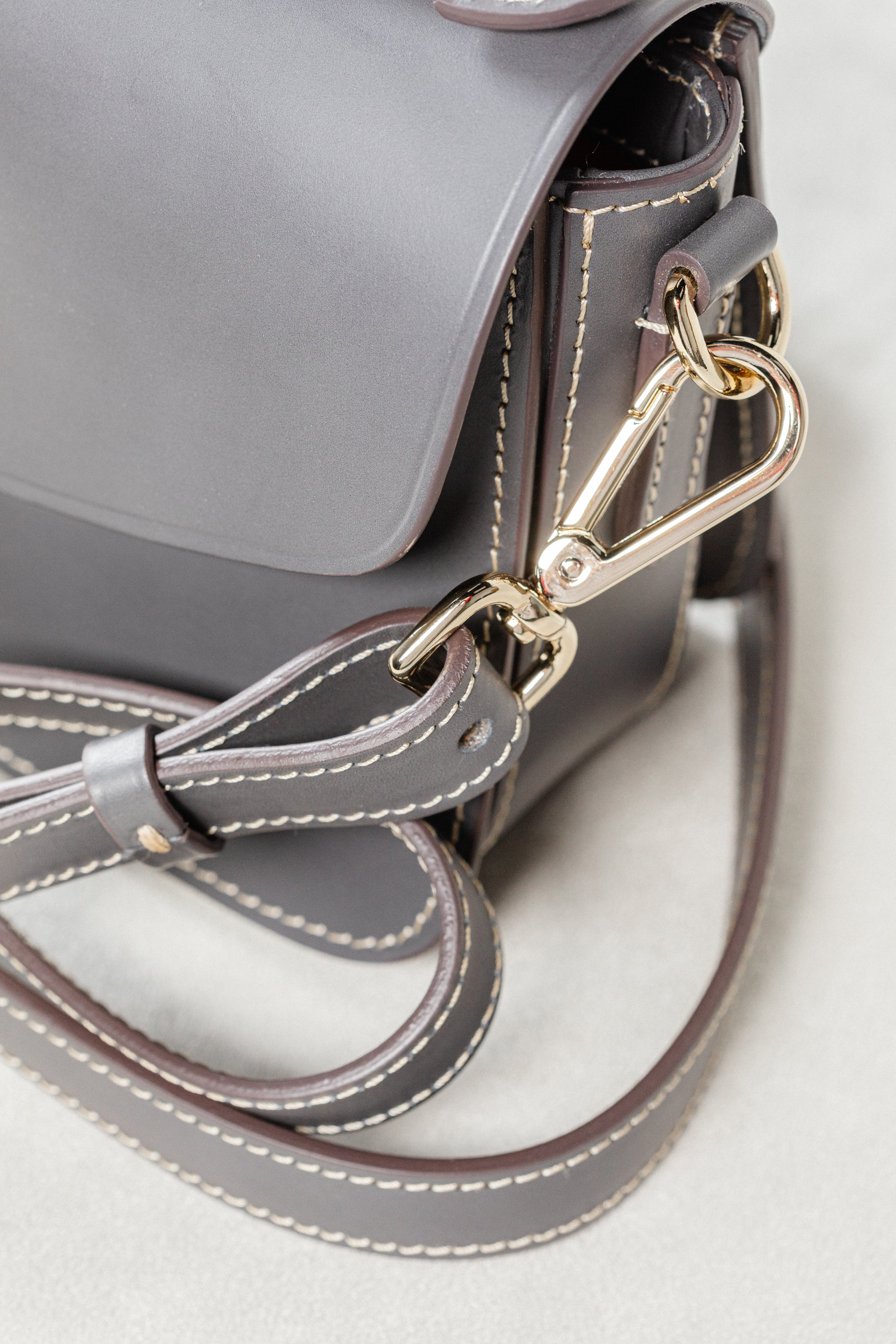 Close-up of grey leather Mantelet Bag by Freedman's, highlighting gold-tone clasp hardware, adjustable strap, and contrasting stitching.