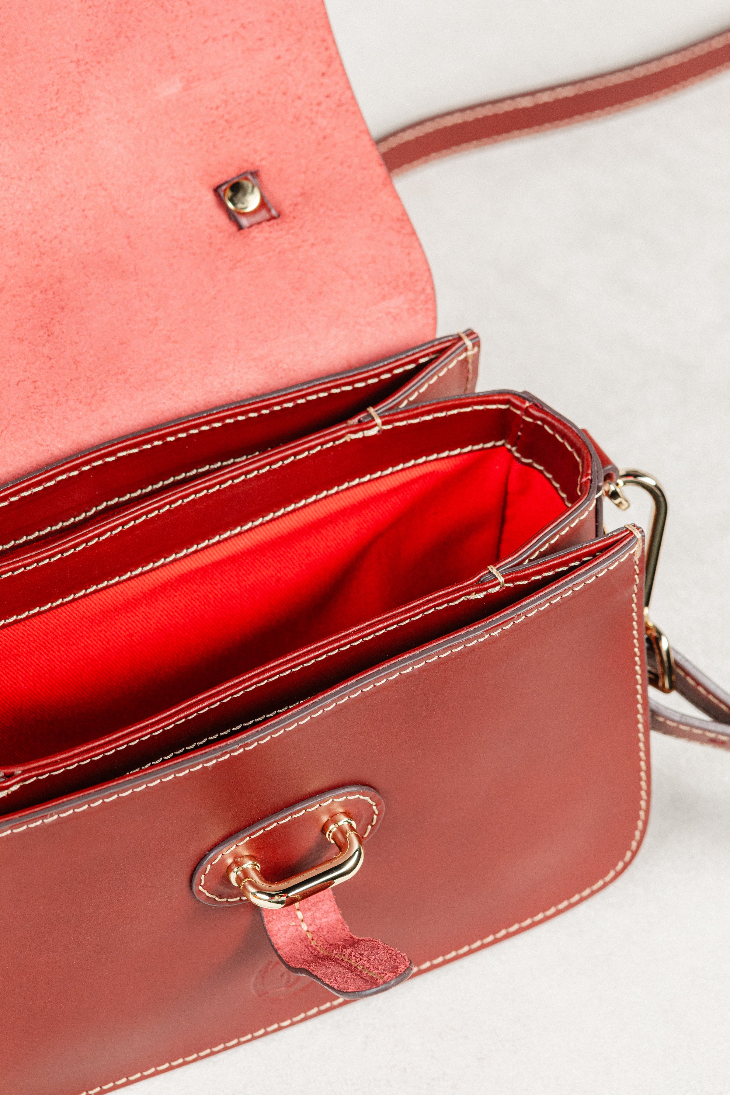 Close-up of Brunello leather Mantelet Bag by Freedman's, highlighting red interior lining, gold-tone hardware, and contrasting stitching.