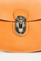 Close-up of cognac leather Minibus Bag by Freedman's, highlighting gold-tone turn-lock closure and embossed brand logo.