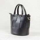 Angled view of black leather Milord Bag by Freedman's, showing woven design, structured handles, and gold-tone hardware.