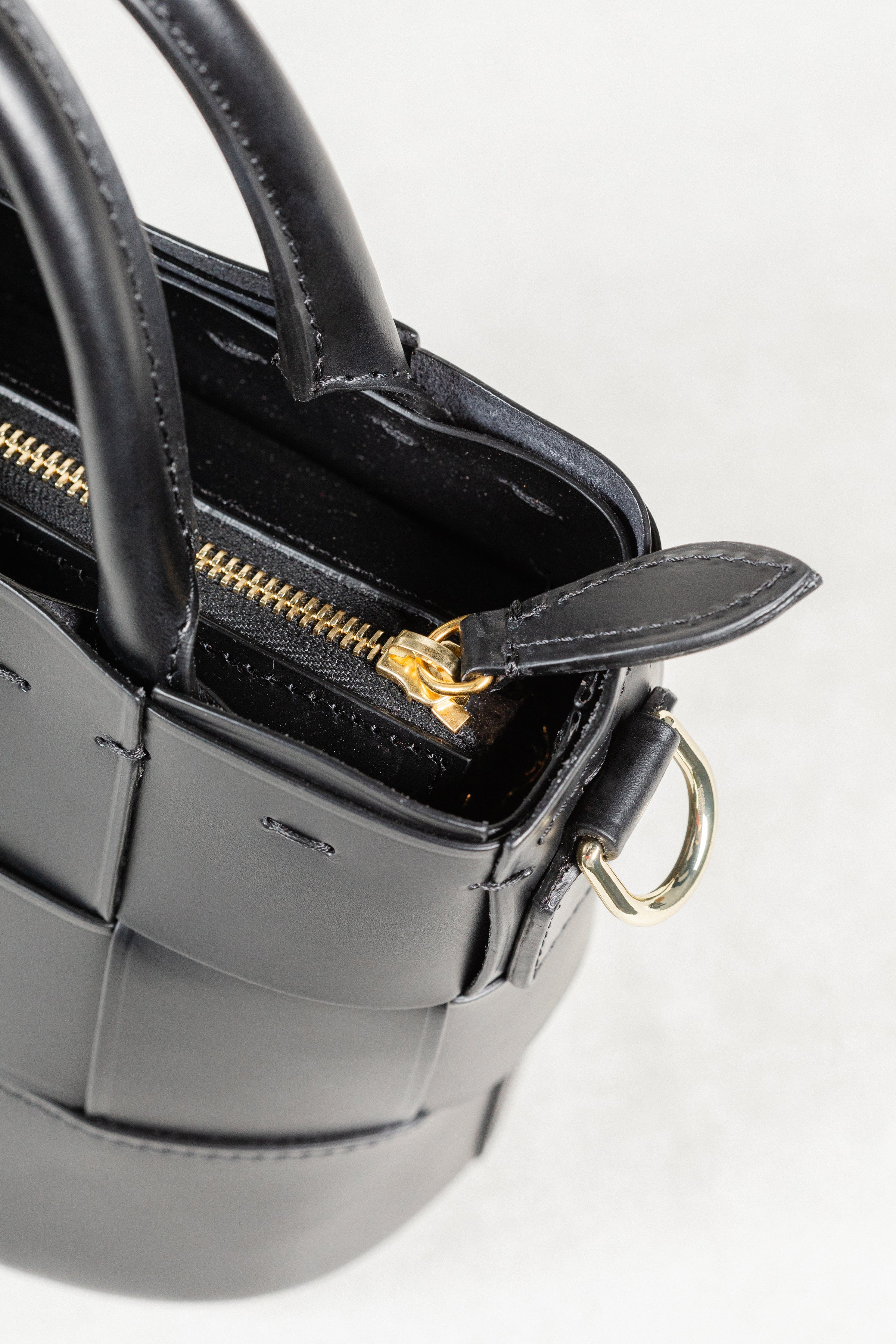 Close-up of black leather Milord Bag by Freedman's, highlighting gold-tone zipper and ring hardware.