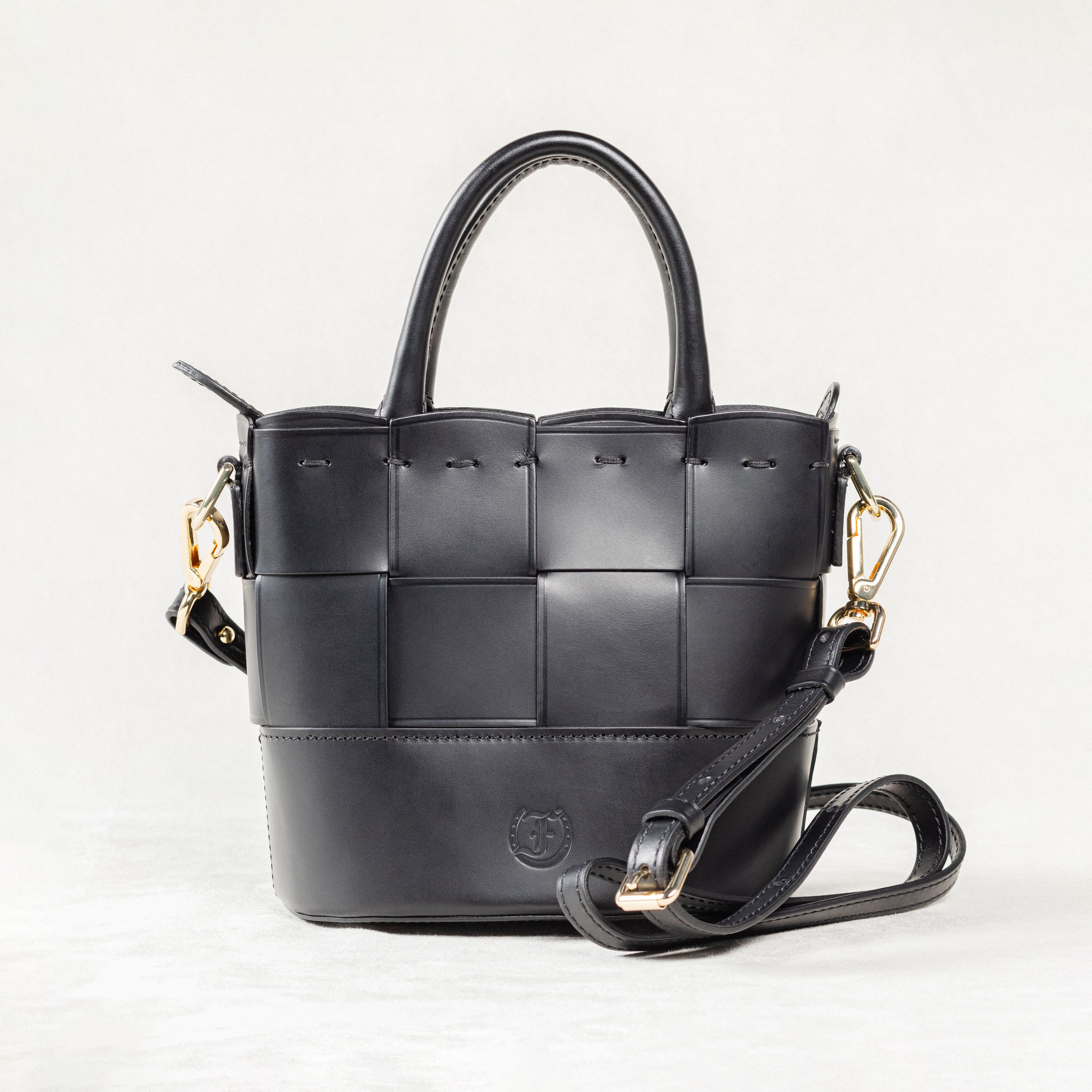 Front view of black leather Milord Bag by Freedman's, showing woven design, gold-tone hardware, and adjustable strap.