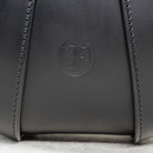 Close-up of black leather Moray Bag by Freedman's, highlighting embossed brand logo and detailed stitching.