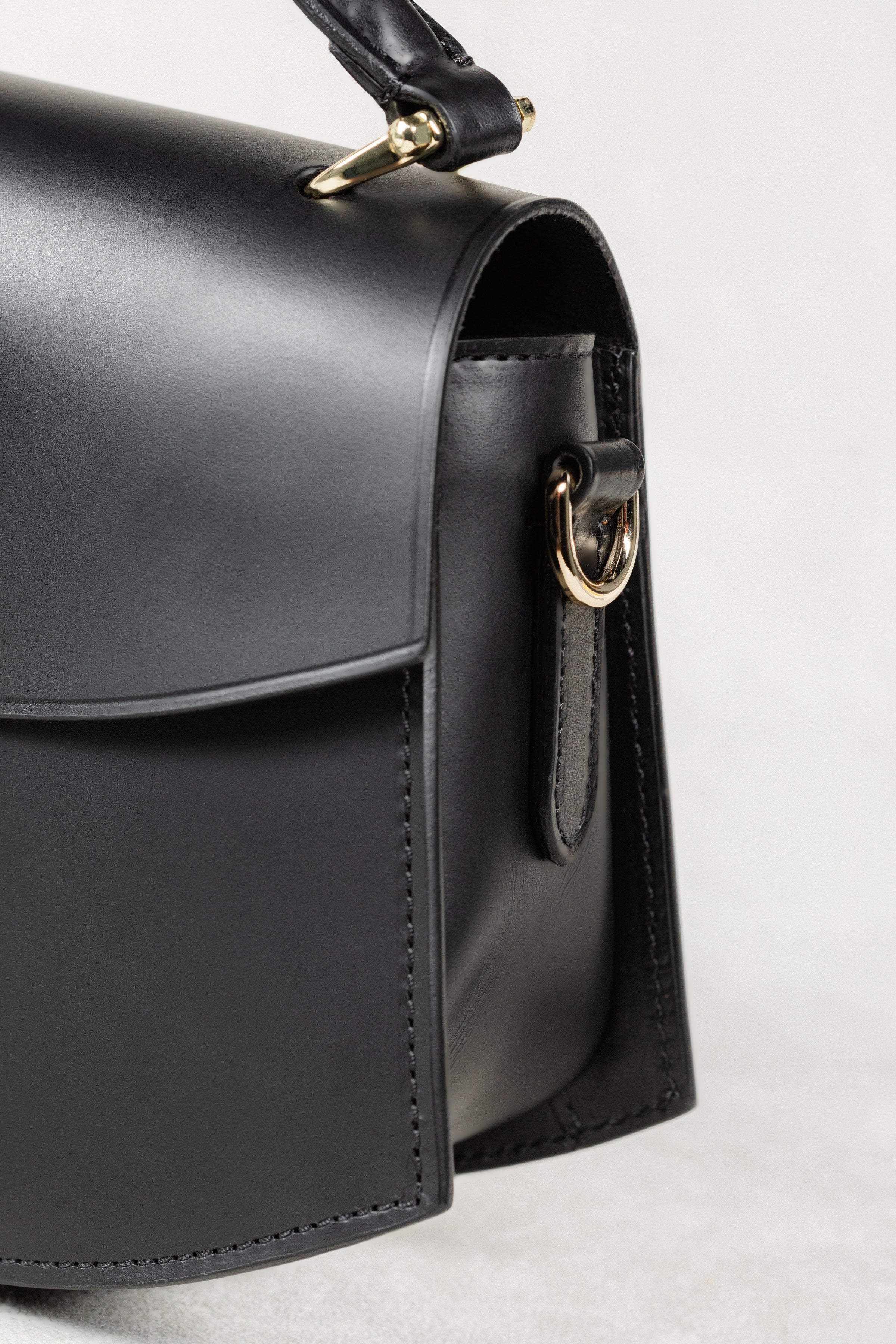 Close-up of black leather Minibus Bag by Freedman's, highlighting gold-tone ring hardware and structured side profile.