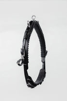Black leather horse neck strap with silver buckles and hardware, hanging against a white background.
