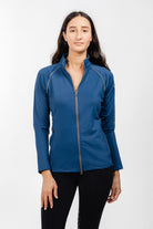 Ladies Arum Jacket by Freedman's in navy blue with silver zipper detail and reflective piping, front view on woman with long dark hair against white background, styled with black athletic pants, showcasing athletic apparel fit