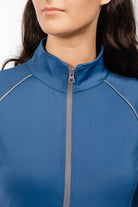 Close-up detail of Ladies Arum Jacket by Freedman's in purple, showing high collar design, black zipper, and contrast piping construction, highlighting quality stitching and fabric texture on woman with dark hair against white background