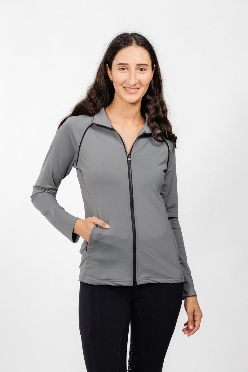 Ladies Arum Jacket by Freedman's in gray with black zipper detail, modeled by smiling woman with long dark hair wearing black pants against white background, showing athletic apparel fit and style