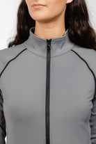 Close-up detail of Ladies Arum Jacket by Freedman's in gray, showing high collar design, black zipper, and contrast piping construction, highlighting quality stitching and fabric texture on woman with dark hair against white background