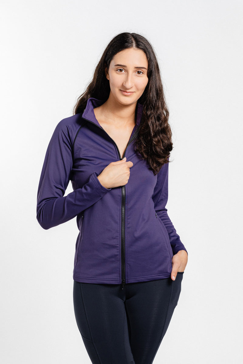 Ladies Arum Jacket by Freedman's in purple with black zipper, modeled by woman with long dark hair against white background, shown with one hand on zipper and other in pocket, paired with black athletic pants