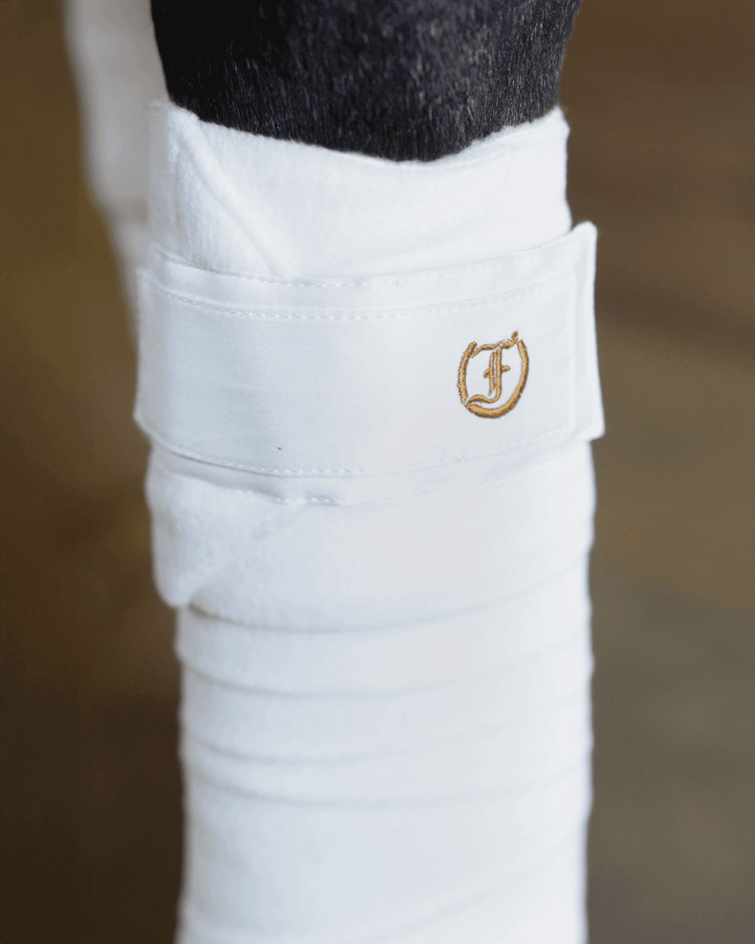 Close-up of white Freedman’s Signature Polo Wrap with embroidered logo on horse leg